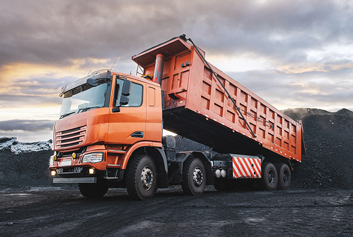 A picture of an orange tipper truck in a quarry.