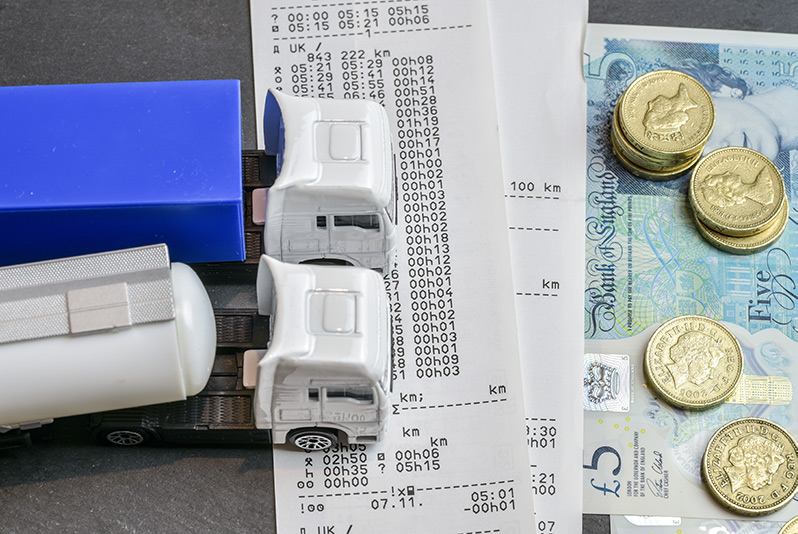 A tachograph print under toy tracks and one pound coins.